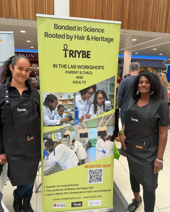 TRIYBE team members in TRIYBE aprons beside the In the Lab: Bonded in Science workshop banner